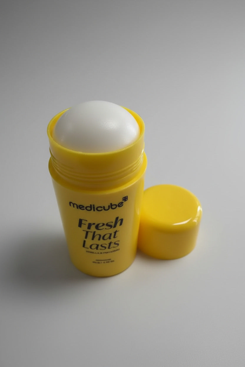 Yellow lip balm container with white cap on a white surface, keyboard in the background